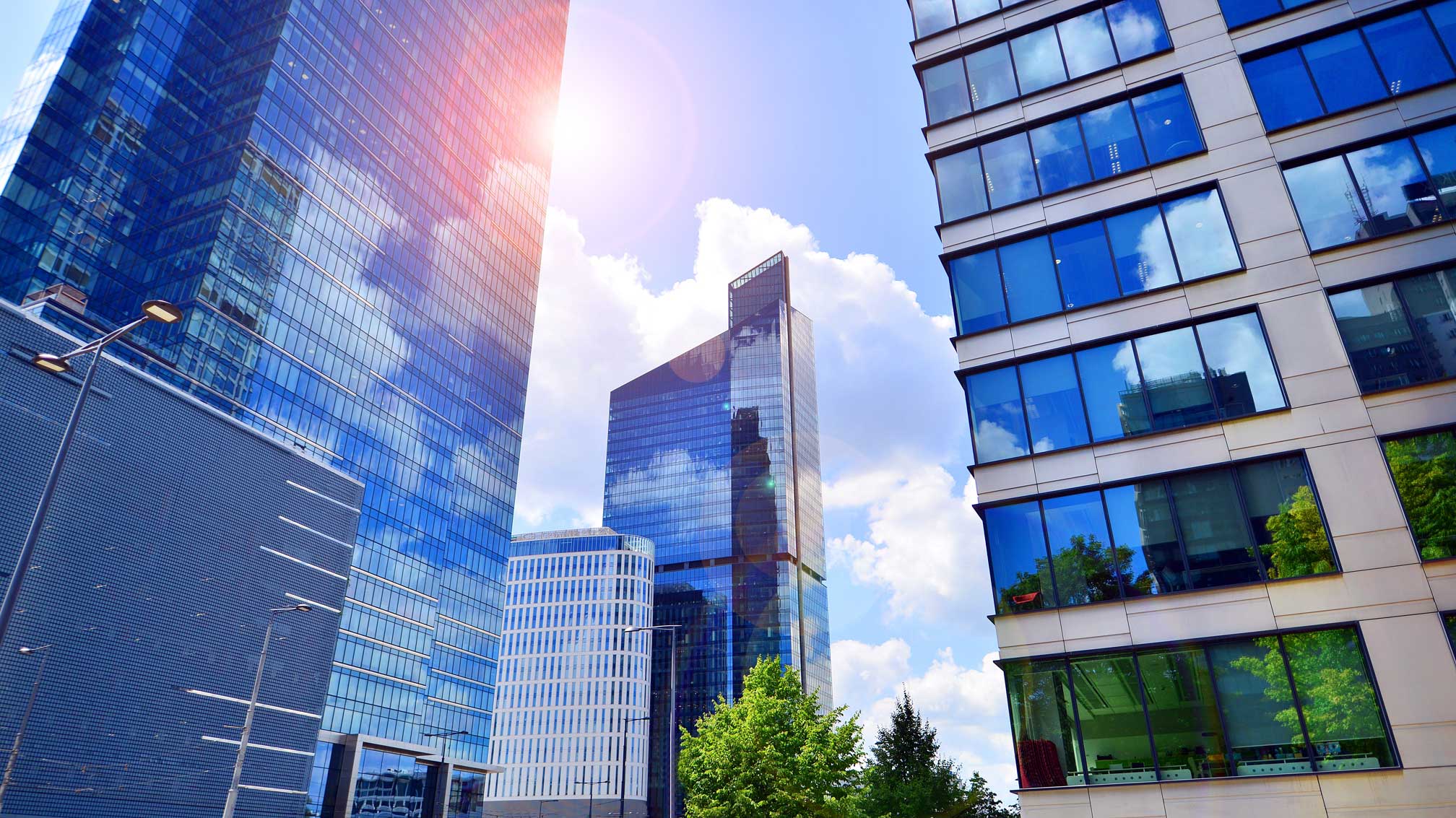 TOP Sustainable Building Practices for 2024 | Wint Blog: Glass facade of the buildings with a blue sky. Skyscrapers in the business city center.. Background of modern glass buildings.
